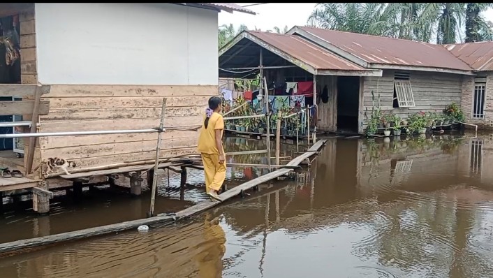 Salah seorang warga tampak  berada di halaman depan rumah tergenang banjir.(Foto/Edi) 